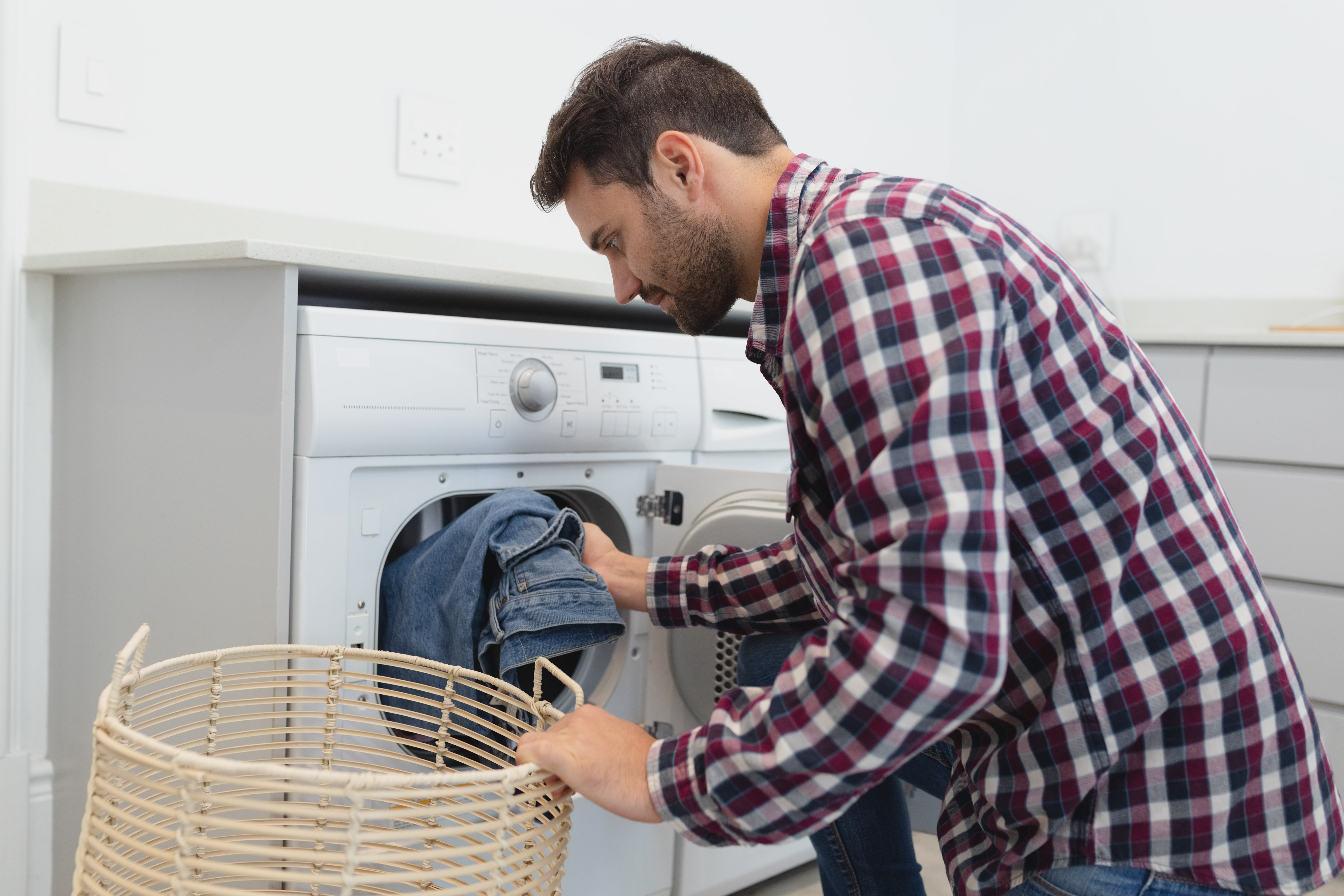 side-view-of-caucasian-man-putting-dirty-clothes-QVYK5FL-min